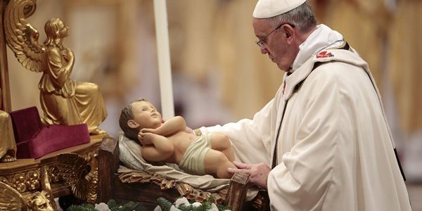 Pope Francis holds the baby Jesus statue as he leads the Christmas night mass in the Saint Peter's Basilica at the Vatican