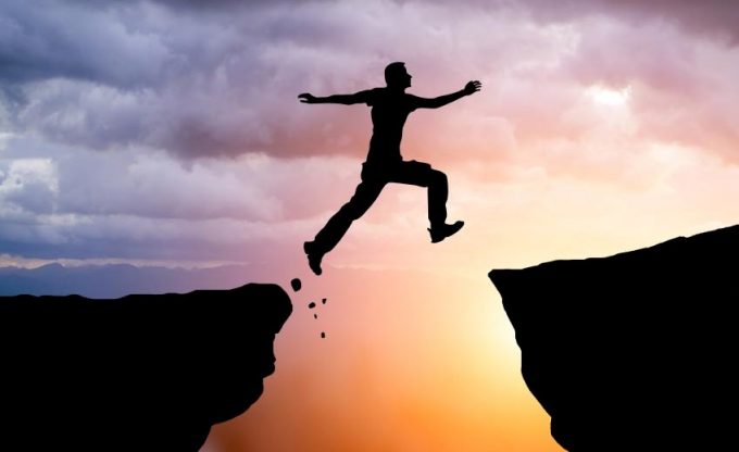 Silhouette of hiking man jumping over the mountains