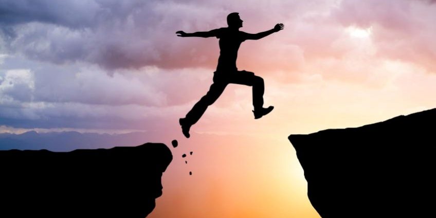 Silhouette of hiking man jumping over the mountains