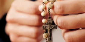 Woman praying with rosary to God