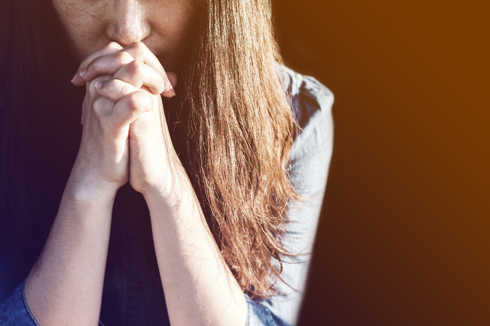 Woman praying in meadow at sunset