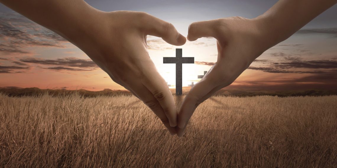 People hand making heart sign with bright cross inside