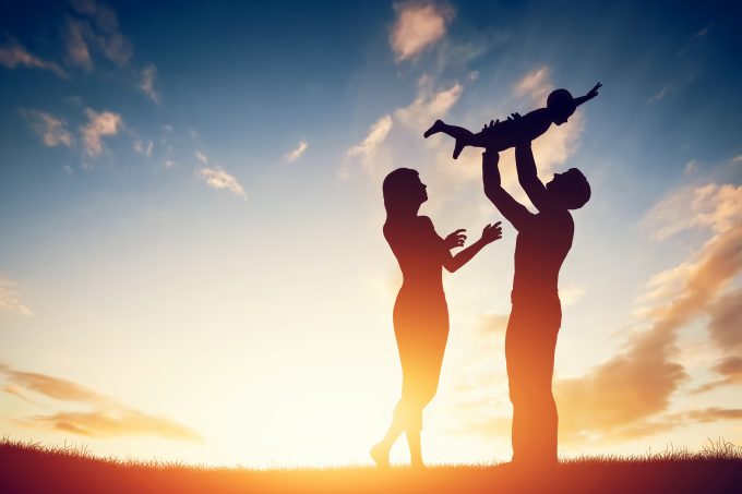 Happy family together, parents with their little child at sunset.