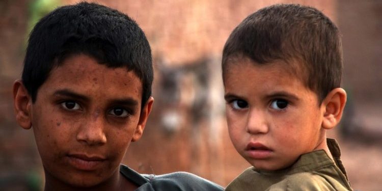 criancas-afegas-refugiadas Dois meninos afegãos olhando para a câmera; um é mais velho e o outro mais novo.