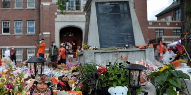 memorial-indigena-escola-catolica Flores, bonecas e ursos de pelúcia em memorial na frente de terreno da antiga Escola Residencial Indígena Kamloops, no Canadá