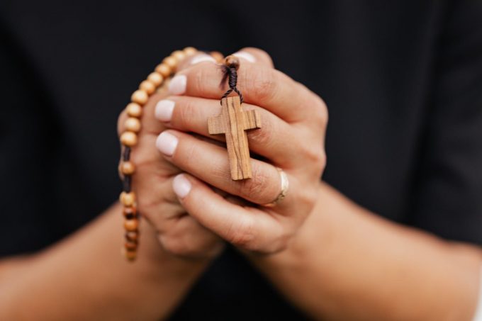 oracao-missao-paz-mocambique Mãos juntas em oração e segurando um terço de madeira.