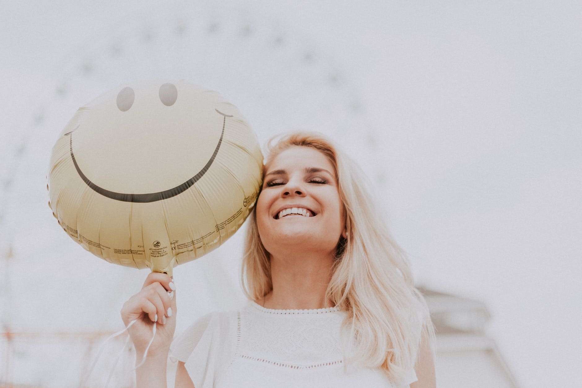 palavras-bondosas Mulher sorrindo e segurando um balão amarelo com uma cara feliz.