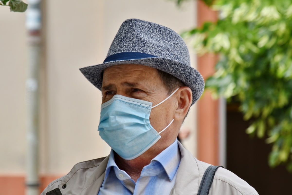 por-que-usar-mascara-depois-vacina Homem idoso usando máscara e chapéu.
