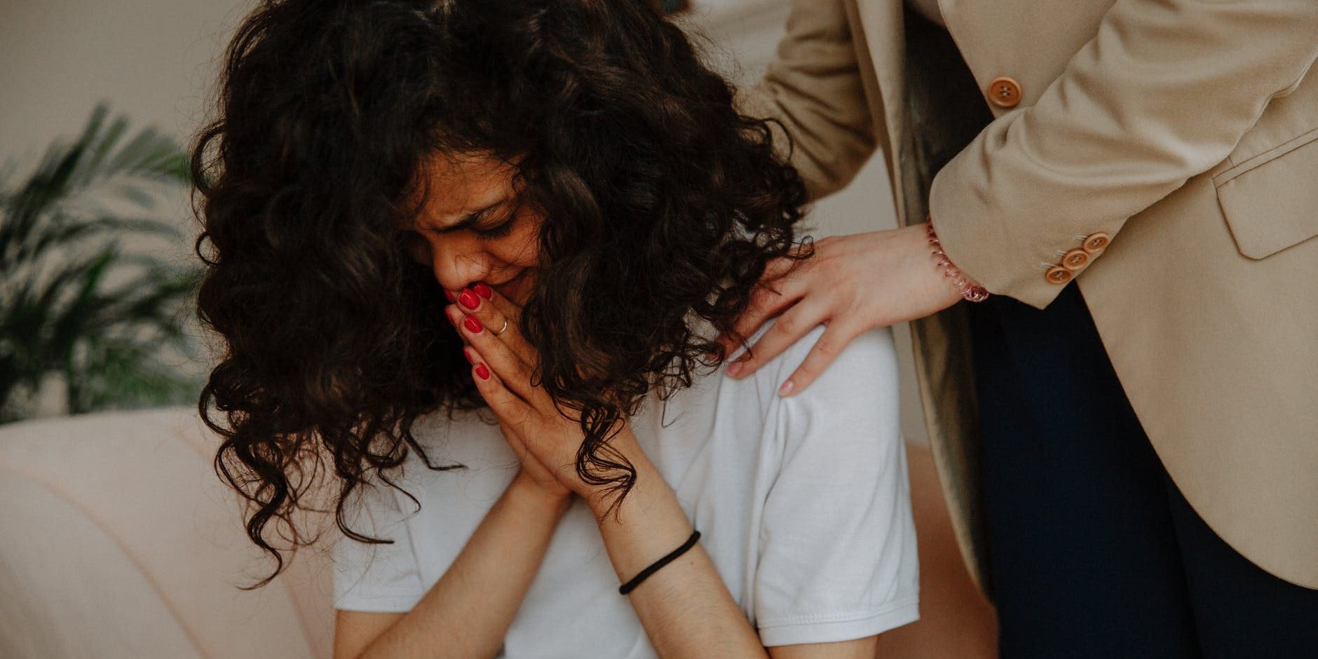 saude-mental Mulher chorando de cabeça baixa; uma pessoa segura seus ombros de maneira reconfortante