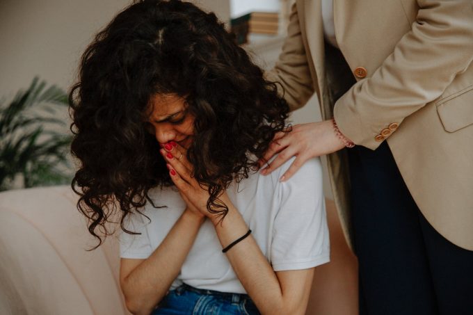 saude-mental Mulher chorando de cabeça baixa; uma pessoa segura seus ombros de maneira reconfortante