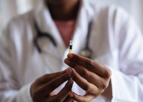 vaticano-vacinar-pobres Médico segurando seringa com agulha.