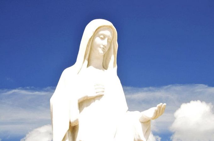 virgem-maria Estátua da Virgem Maria em Medjugorje na frente de um céu azul com nuvens brancas
