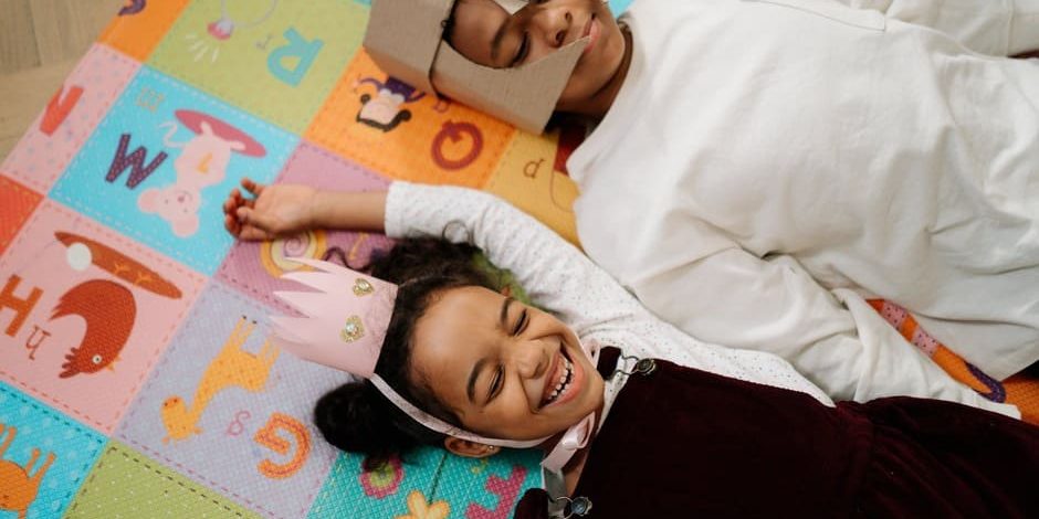 Menino e menina deitados em tapete colorido.