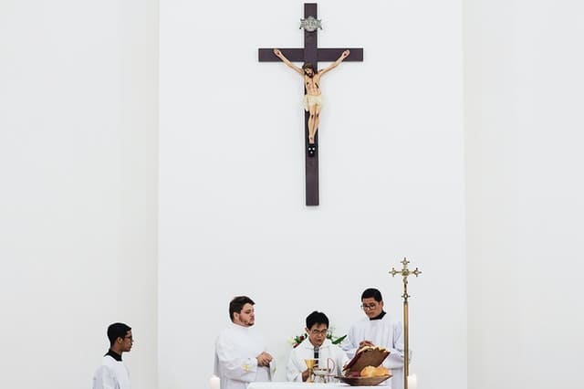 pexels-marcelo-chagas-1782330 (1) Sacerdote usando microfone na frente de uma parede branca com a imagem de Jesus crucificado