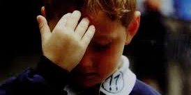 Menino fazendo sinal da cruz sobre a testa.