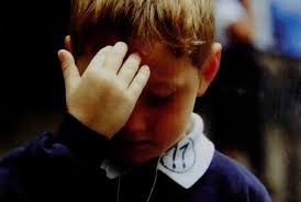 Menino fazendo sinal da cruz sobre a testa.
