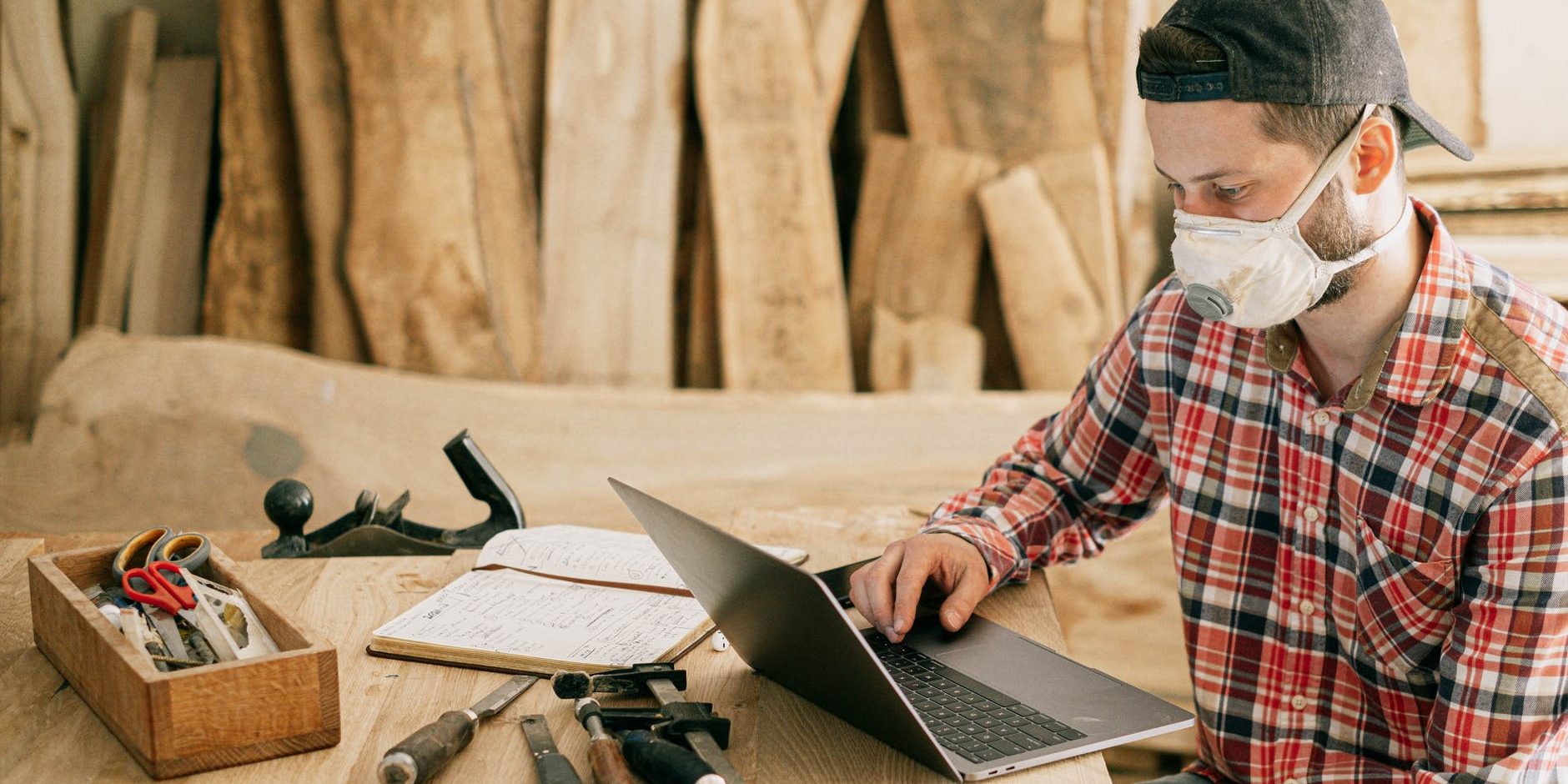 trabalho Homem usando o notebook em um ambiente de madeira e cheio de ferramentas diversas.