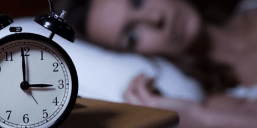 3-da-manha Relógio marcando 3 horas e mulher deitada ao fundo