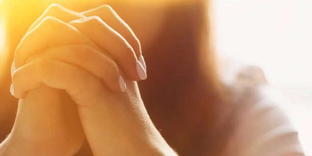 Cute beautiful girl folded her hands in prayer. A woman asks God for help.